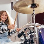 YoungGirlPlayingDrumsHappyandSmilingCover